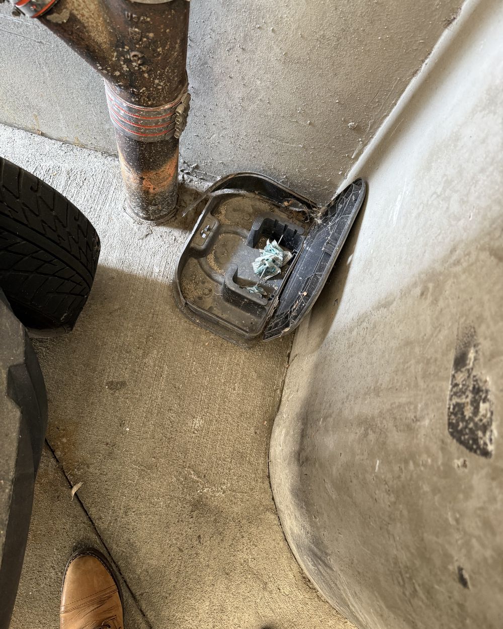 Rodent bait station in a parking structure sitting open and filled with spider webbing, showing it has not been serviced in months